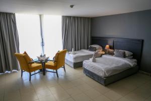 索瓦马O Beach Hotel & Resort的酒店客房带两张床和一张桌子以及椅子。