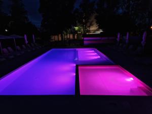 希欧福克Colors Holiday Hotel的游泳池晚上点亮紫色的灯光
