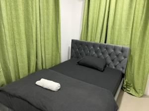 拉巴萨Bula Homestay的一张带床头板的床、一个枕头和绿色窗帘