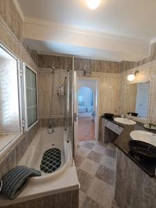 奥良Lovely new House - Guests Apartments的带浴缸、两个盥洗盆和淋浴的浴室。