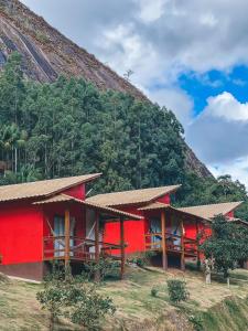 新文达移民镇Chalés Vale das Pedras的山前的红色房子