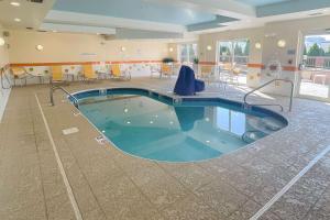 亚克朗Comfort Inn & Suites Akron South的游泳池位于带桌椅的房间中间
