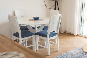 昆博White Apartment的一张带四把椅子的白色桌子和一碗