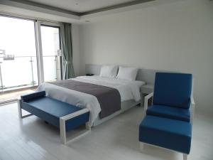 西归浦市汉拿山度假村的一间卧室配有一张床和一张蓝色椅子