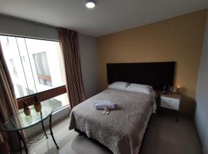 利马Inti Llaqta Hotel & Suites的一间卧室配有一张带玻璃桌和窗户的床