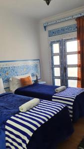 舍夫沙万家庭旅馆的一间卧室配有3张蓝色和白色条纹的床