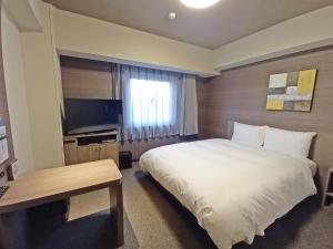 ChuoHotel Route-Inn Yamanashi Chuo的酒店客房,配有床和电视
