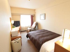 横滨HOTEL LiVEMAX BUDGET Yokohama Kannai的配有一张床和一把椅子的酒店客房