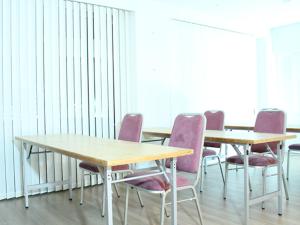 横滨HOTEL LiVEMAX BUDGET Yokohama Kannai的一间会议室,配有两张桌子和紫色椅子
