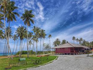Kampong Pasir PutehMILLBROOK HOUSE TERENGGANU的一座棕榈树成荫的红色建筑,位于大海前