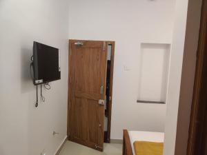蒂鲁琴杜尔SRI BALAJI LODGING的一间有门的房间,墙上有一台电视机