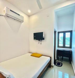 蒂鲁琴杜尔SRI BALAJI LODGING的一间白色的小房间,配有床和电视