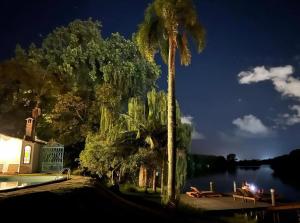 佩洛塔斯Charqueada Santa Rita Pousada de Charme的棕榈树在湖边的夜晚