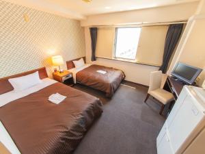 相模原市HOTEL LiVEMAX BUDGET Sagamihara的酒店客房设有两张床和电视。