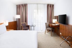 布达佩斯奥普拉K+K酒店的酒店客房配有一张床、一张书桌和一台电视。