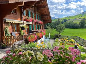 格施塔德Alpenchalet Spiher Gstaad Ferienwohnung im Parterre的鲜花屋前的花园