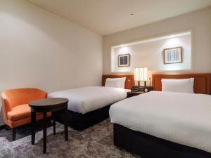 福冈JR九州福冈花博酒店的酒店客房,配有两张床和椅子