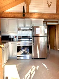 Gillies BayThe Beach House Texada - Waterfront Cabin的厨房配有不锈钢冰箱和白色橱柜