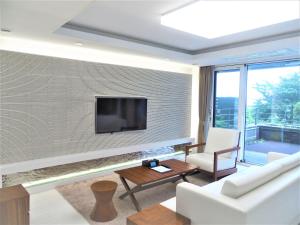 西归浦市汉拿山度假村的一间客厅,在砖墙上配有电视