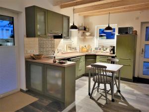FockbekHaus Theda的厨房配有绿色橱柜和桌椅
