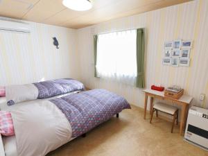 美瑛町Pension Ken&Mary的一间卧室配有一张床、一张桌子和一个窗户。
