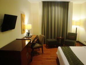 美娜多美娜多品质酒店的酒店客房配有一张床、一张书桌、一张床和一张书桌。