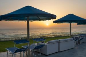 塔哈佐特Pickalbatros White Beach Taghazout - Adults Friendly 16 Years Plus - Ultra All Inclusive的一个带椅子和遮阳伞的庭院和大海