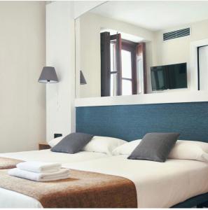 阿尔卡拉德荷那利斯米格尔·德·塞万提斯酒店的一间卧室设有两张床和大镜子