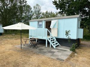 BarkelsbyTiny Beach House的蓝色的小房子,配有桌子和雨伞