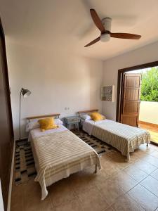 圣何塞Casa con piscina en San José Sotillo的一间卧室配有两张床和吊扇