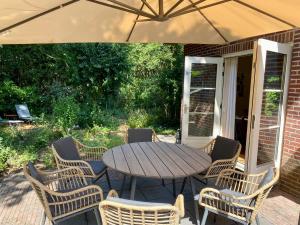伊皮Huisje aan de Bosrand - Veluwe的庭院里配有一张木桌和椅子及遮阳伞