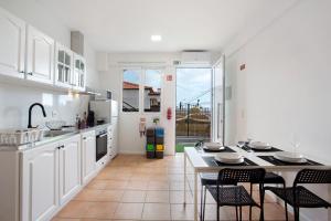 丰沙尔Babosas Charm的厨房配有白色橱柜和桌椅