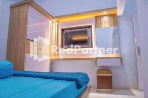PalopoHotel Rai's Palopo Exclusive Mitra RedDoorz的一间卧室配有蓝色的床和电视