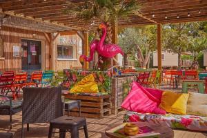 纳博讷普拉日Mobil-home (Clim, Tv)- Camping Narbonne-Plage 4* - 022的庭院设有粉红色火烈鸟雕像和椅子