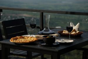 西格纳吉Signagi Glamping的一张桌子,上面放着两杯葡萄酒和比萨饼