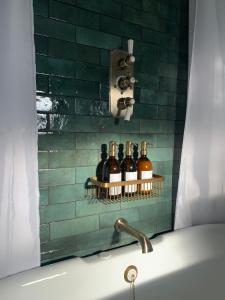 莱奇莱德Cosy Cottage in Lechlade的浴室位于浴缸旁的架子上,配有瓶装葡萄酒