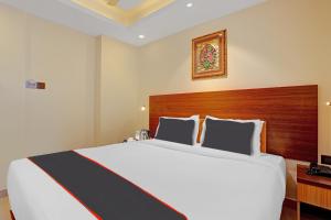 特里凡得琅Hotel Pallava Rajadhani的卧室配有一张白色大床和木制床头板