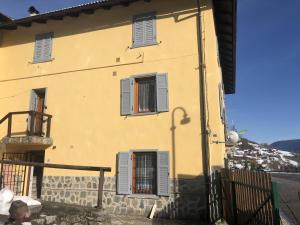科姆梅扎杜拉Ride Home - Val di Sole的黄色的房子,有三扇窗户和栅栏