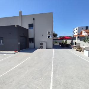 扎达尔Apartments Anamarija的白色建筑前的停车场