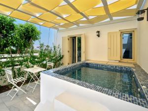 纳乌萨Villa Maria - Naoussa Surfers Bluewave Suite的一座带桌椅的别墅内的游泳池