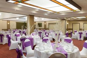 克兰菲尔德克兰菲尔德管理发展中心酒店的宴会厅配有白色桌子和紫色椅子