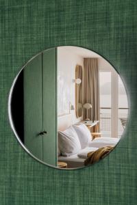 卢塞恩HERMITAGE Lake Lucerne - Beach Club & Lifestyle Hotel的一间卧室设有一面带镜子的绿色墙壁