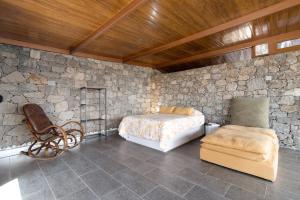 圣布里希达La Casita de la Orilla de Peñate的一间卧室配有一张位于石墙内的床铺和一把椅子