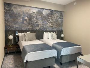 蒂萨新城Tisia Hotel & Spa的一间卧室设有两张床,墙上挂着一幅画