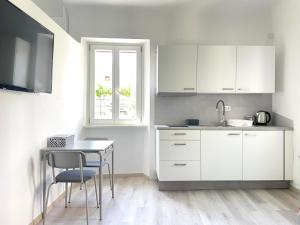 科佩尔Koper Relax home的厨房配有白色橱柜、桌子和窗户。