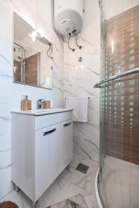 比比涅Apartments MENA的带淋浴和盥洗盆的白色浴室