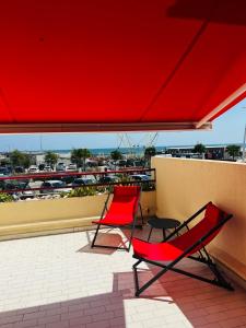 帕拉瓦莱弗洛RAINIE APPART的两把红色椅子坐在带红伞的阳台上