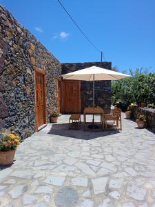 IsoraCasa Rural LUCÍA的一个带桌子和遮阳伞的庭院