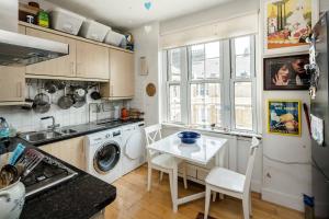 伦敦Stylish Central London Flat Near Tower Bridge的厨房配有洗衣机和桌子