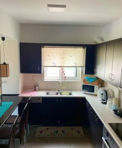 新马克立Sweet Makri Suite的厨房配有蓝色橱柜、水槽和窗户。